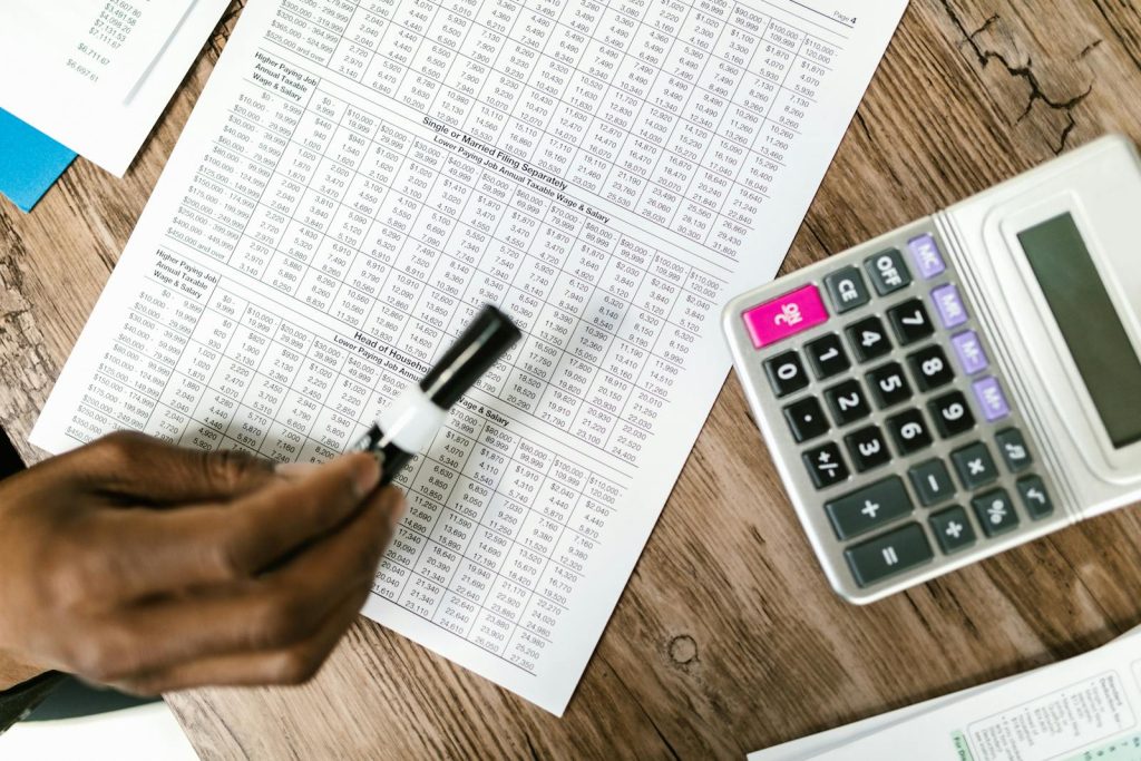 Close-up of tax documents and calculator on wooden table, highlighting financial analysis.